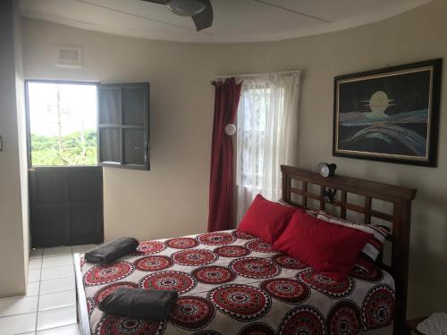 Un dormitorio con una cama con almohadas rojas y una ventana. en Oceanic, en Scottburgh
