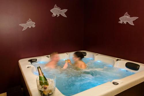 two children in a hot tub with a bottle of champagne at Les Lavandières de Fontaine in Fontaine-lès-Vervins