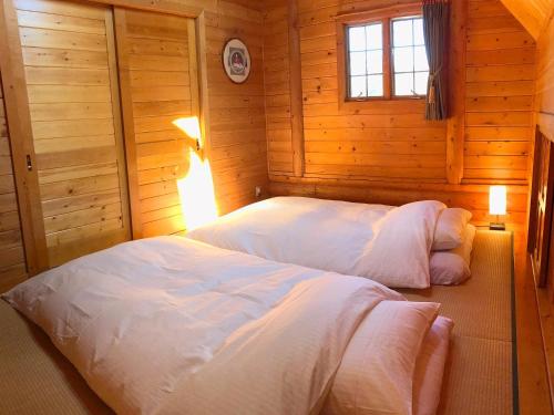 A Private Log House with Mt Fuji View & Piano - "Thangtong House Japan" في Kannami: غرفة نوم بسريرين في غرفة خشبية