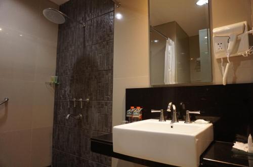 雅加達的住宿－珊迪卡卡拉巴加丁酒店，浴室配有盥洗盆和带镜子的淋浴