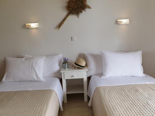 2 Betten mit weißen Kissen und einem Tisch mit Hut in der Unterkunft Corfu Olivia Apartments in Moraḯtika