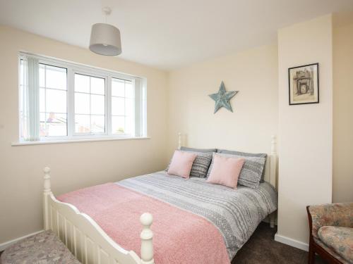 a bedroom with a bed with a pink and gray blanket at Yr Hafan in Colwyn Bay