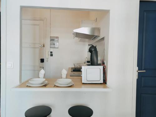 - une petite cuisine avec une table et un four micro-ondes dans l'établissement Joli Studio - Promenade des Anglais - Accès plage, à Nice