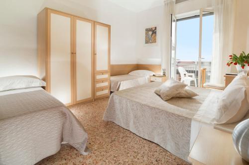 リミニにあるHotel Bellerofonteのベッド2台と大きな窓が備わるホテルルームです。