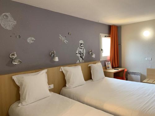 une chambre d'hôtel avec 2 lits et un mur avec des autocollants dans l'établissement initial by balladins Tours Sud, à Chambray-lès-Tours