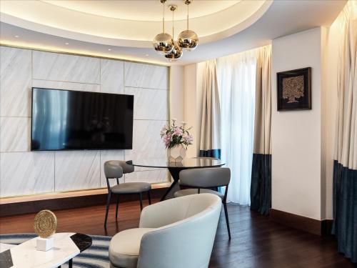a living room with a table and chairs and a tv at Athens Capital Center Hotel - MGallery Collection in Athens