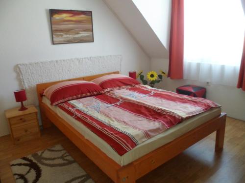 a bedroom with a bed with red sheets on it at Makai Apartman in Hajdúszoboszló
