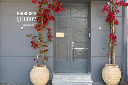 two large vases with flowers in front of a door at Kalamata Art Rooms in Kalamata