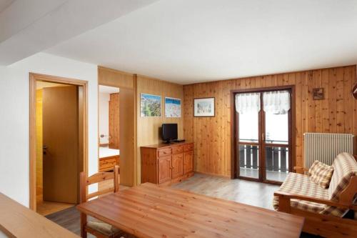 un soggiorno con tavolo in legno e TV di Casa Dolomiti a Moena