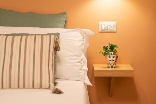 a bed with a nightstand with a vase with a plant on it at Autentica Ortigia in Siracusa