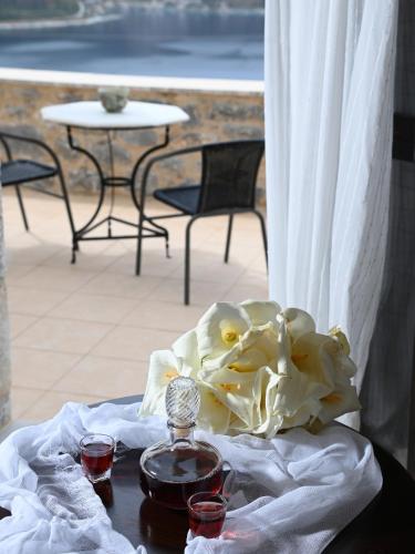a table with a bouquet of flowers and two glasses at Selana View in Karavostasion