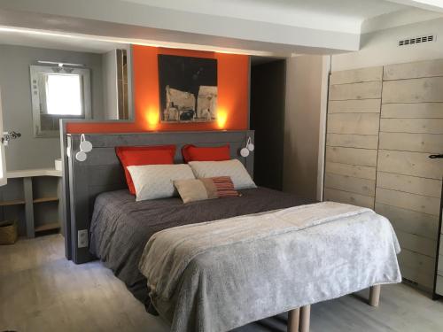 Un dormitorio con una cama con una pared naranja. en La 54 Provence, en LʼIsle-sur-la-Sorgue