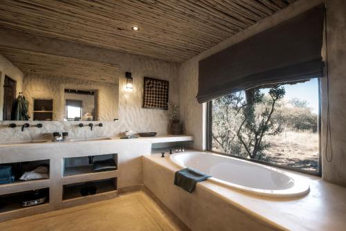 ein großes Bad mit einer Badewanne und einem Fenster in der Unterkunft Zannier Hotels Omaanda in Ondekaremba