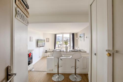 a white kitchen with a counter and two stools at Deauville-Port - Escapade Deauvillaise dans un charmant studio in Deauville