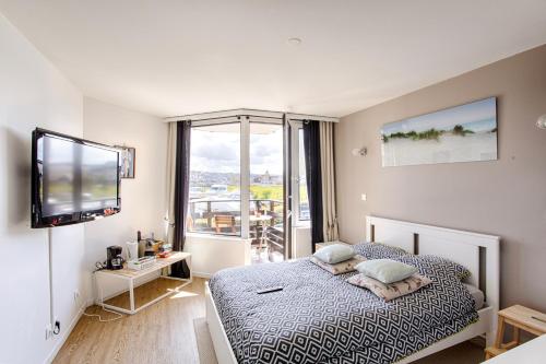 um quarto com uma cama, uma televisão e uma janela em Deauville-Port - Escapade Deauvillaise dans un charmant studio em Deauville