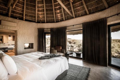 ein Schlafzimmer mit einem großen Bett in einem Zimmer mit Fenstern in der Unterkunft Zannier Hotels Omaanda in Ondekaremba