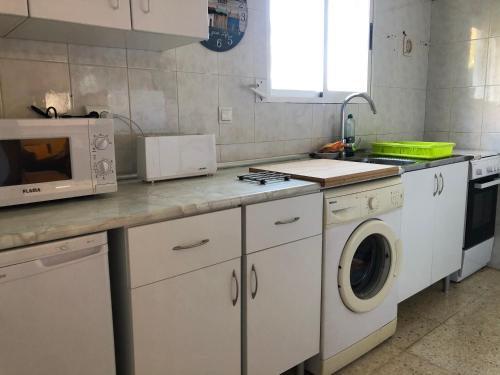 a kitchen with a washing machine and a microwave at Casa El Castellet en Polop. in Polop