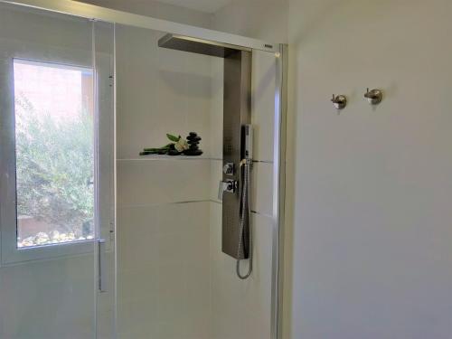 una ducha con una puerta de cristal junto a una ventana en Apartamentos R66 en Cáceres