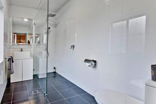 a white bathroom with a shower and a toilet at Elements Of Goulburn in Goulburn