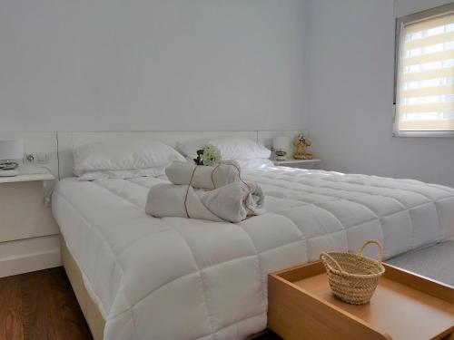 Una gran cama blanca con un animal de peluche. en Apartamentos R66, en Cáceres