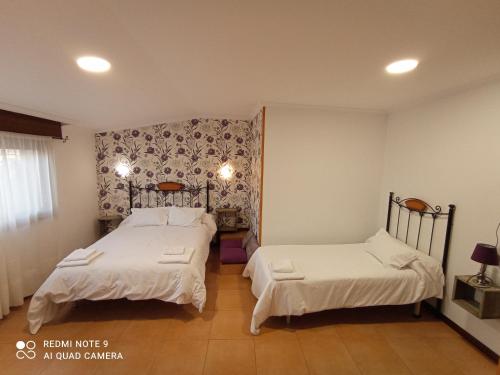 a bedroom with two beds and a wall at Pensión O Escondidino in Baiona