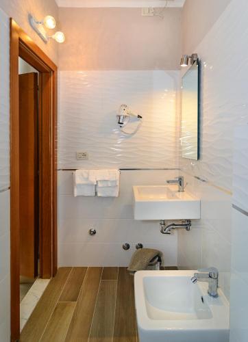 a white bathroom with a sink and a mirror at Villa Grazia in Viareggio