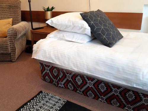 a bed with white sheets and pillows and a chair at Resort Kasprowy Wierch in Zakopane