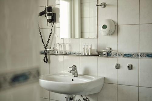 a white bathroom with a sink and a mirror at Sola Strand Hotel in Sola