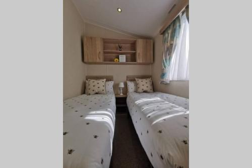 um quarto com três camas e uma janela em 8 Sleep Chalet at Newquay Away Resorts NB160 em Newquay Bay Resort