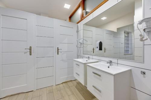 a white bathroom with two sinks and a mirror at Przystanek Sopot Plaża in Sopot