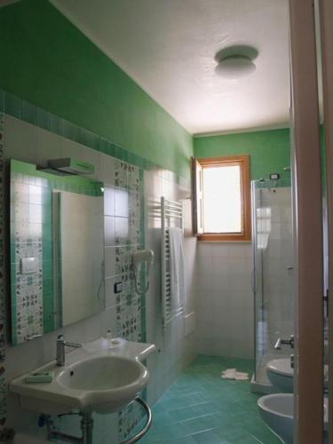 a green bathroom with two sinks and a shower at Santa Caterina Hotel & Apartment in Santa Caterina di Nardò