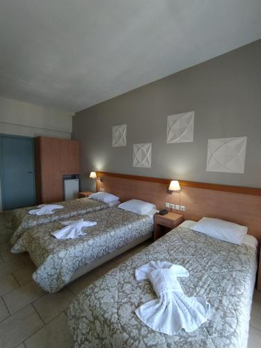 two beds in a hotel room with towels on them at Plaz Hotel in Selianitika