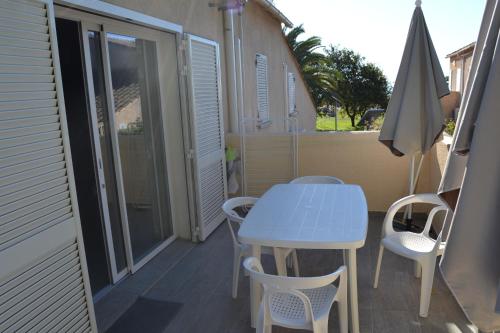 une table et des chaises sur un balcon avec un parasol dans l'établissement H4, à Ghisonaccia