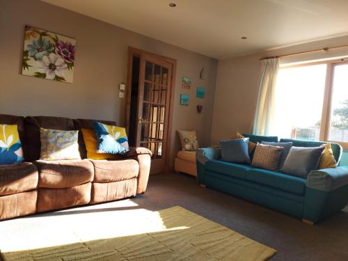 a living room with two couches and a window at Holiday House Kinveachy in Aviemore