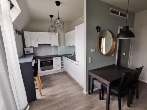 a kitchen with white cabinets and a table and a mirror at Silver Apartments in Wrocław