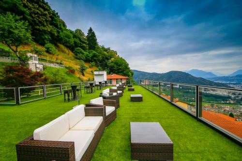a balcony with couches and tables on the grass at Stampa 1968 Hotel e Ristorante in Lavena Ponte Tresa