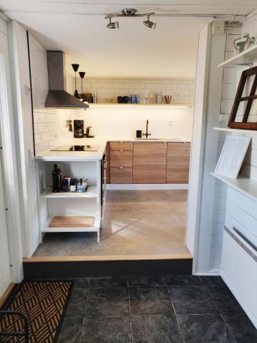 a kitchen with white counters and wooden cabinets at Lillstugan - Centralt och havsnära i lugnt villområde in Falkenberg