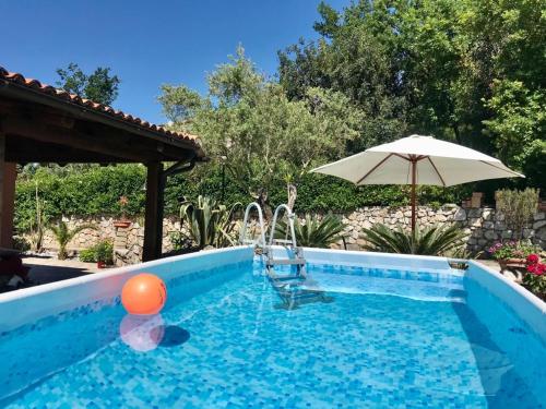 una piscina con ombrellone e una palla arancione in acqua di Villa paradiso a Maratea