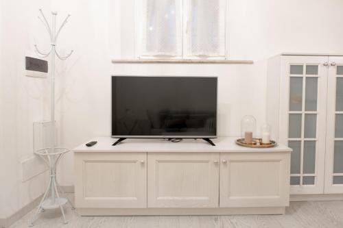 - un salon avec une télévision sur un mur blanc dans l'établissement The Suite Home Verona, à Vérone