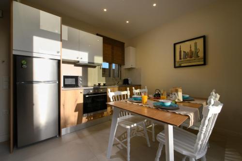 a kitchen with a table with chairs and a refrigerator at Tessera Villas & Studios Collection in Gouvia