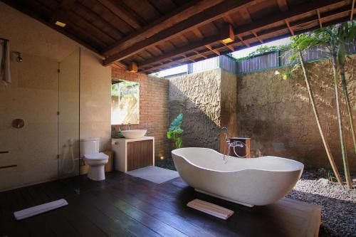 a bathroom with a tub and a sink and a toilet at Taulan Villa by Social Hideout in Kerobokan