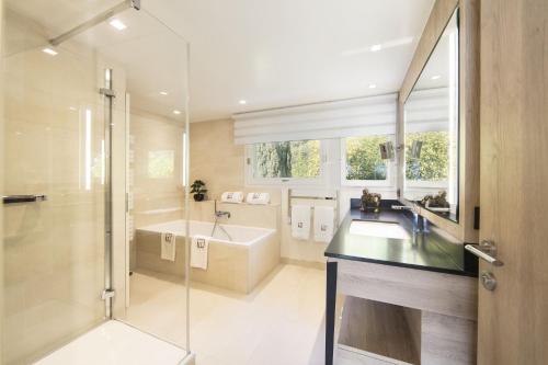 een badkamer met een bad, een wastafel en een douche bij Villa Le France - Vision Luxe in Veyrier-du-Lac