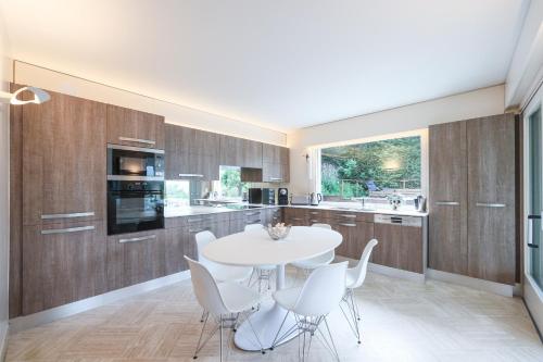 a kitchen with a white table and white chairs at Villa Le France - Vision Luxe in Veyrier-du-Lac