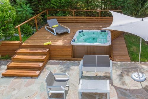 a deck with a hot tub and chairs and an umbrella at Villa Le France - Vision Luxe in Veyrier-du-Lac