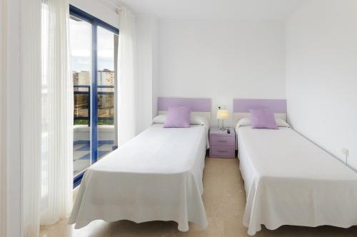 two beds in a white room with a window at Ag Eden Resort in Gandía