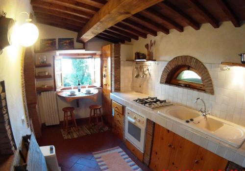 cocina con fregadero y fogones horno superior en Cottage Barbara with aircon, beautiful sea view by ToscanaTour en Casale Marittimo