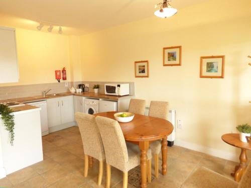 a kitchen and dining room with a wooden table and chairs at Kilkee Holiday Homes Ground Floor in Kilkee