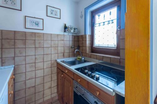 een keuken met een fornuis, een wastafel en een raam bij Casa Riccardo in Soraga