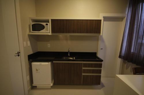 a small kitchen with a sink and a microwave at Hotel Emacite Flex in Mafra