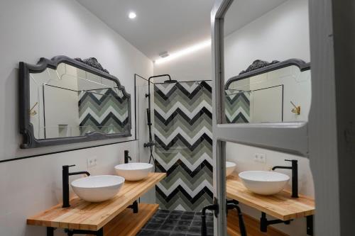 a bathroom with three sinks and two mirrors at Hospederia Santa Clara in Utrera
